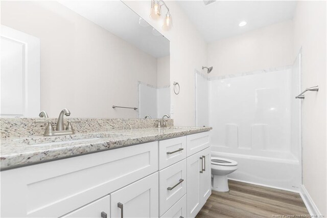 full bathroom featuring dual bowl vanity,  shower combination, toilet, and hardwood / wood-style flooring