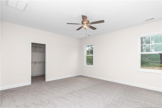 interior space with carpet, a closet, ceiling fan, and a walk in closet