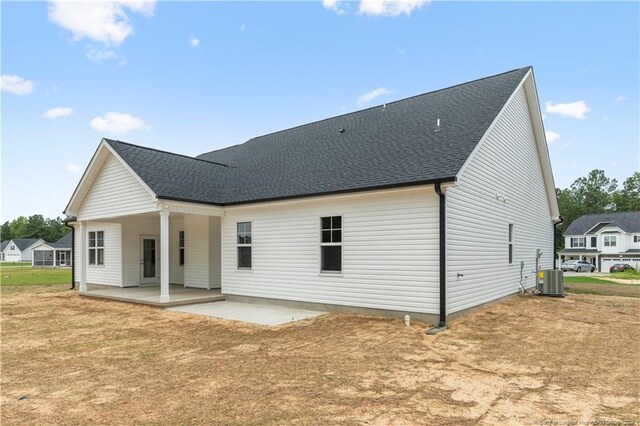 rear view of house with central AC, a lawn, and a patio area