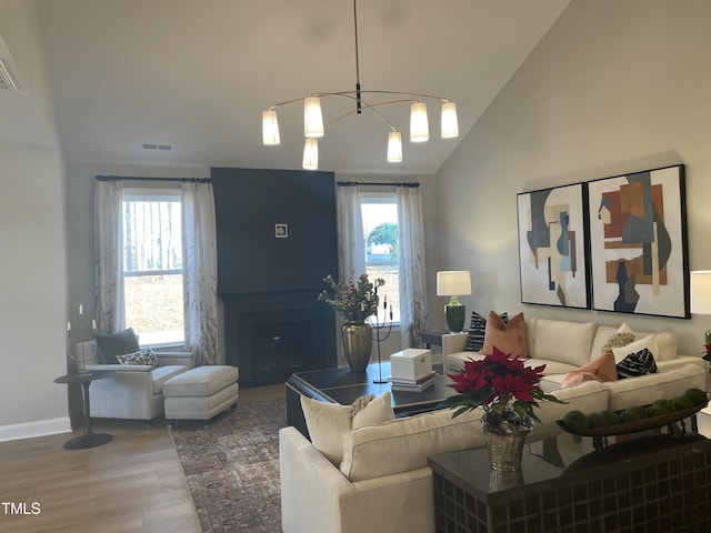 living room with vaulted ceiling, hardwood / wood-style flooring, an inviting chandelier, and a wealth of natural light