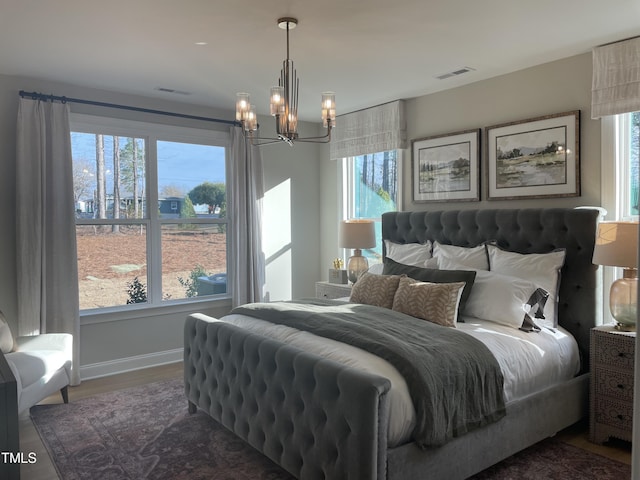 bedroom featuring multiple windows, dark hardwood / wood-style flooring, and a notable chandelier