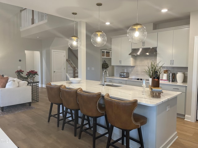 kitchen featuring a kitchen breakfast bar, an island with sink, hanging light fixtures, and sink