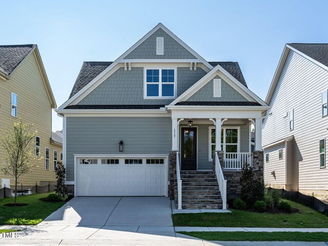 craftsman-style house featuring a garage, a front lawn, and a porch