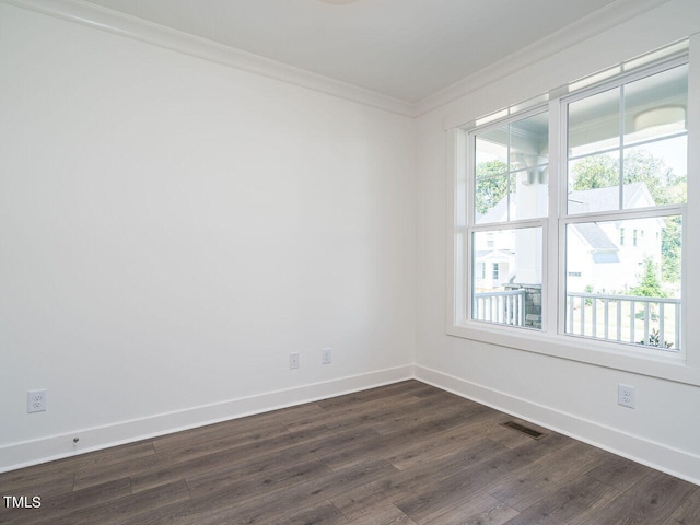 unfurnished room featuring dark wood-type flooring, a healthy amount of sunlight, and ornamental molding