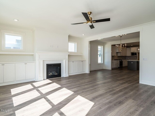 unfurnished living room featuring ceiling fan with notable chandelier, hardwood / wood-style floors, and ornamental molding