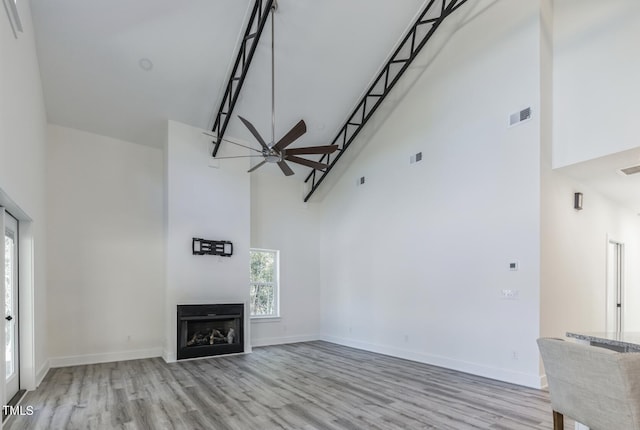 unfurnished living room featuring a high ceiling, hardwood / wood-style flooring, and ceiling fan