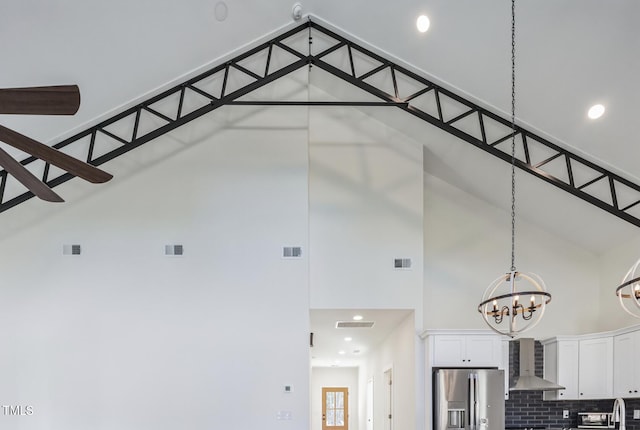 interior space with a high ceiling and ceiling fan with notable chandelier