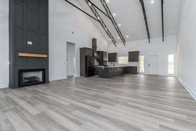 unfurnished living room with a high ceiling, a large fireplace, and light wood-type flooring