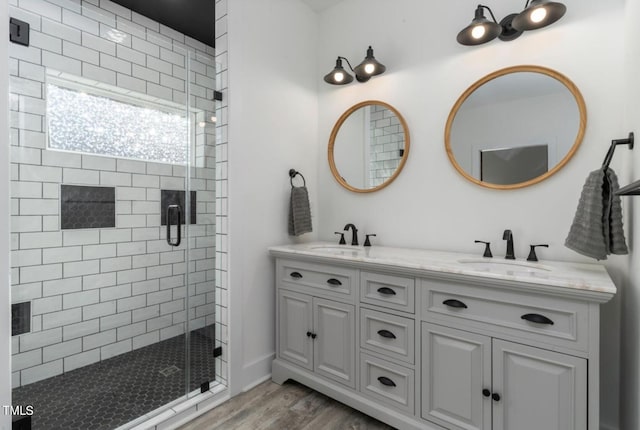 bathroom featuring dual vanity, an enclosed shower, and hardwood / wood-style floors