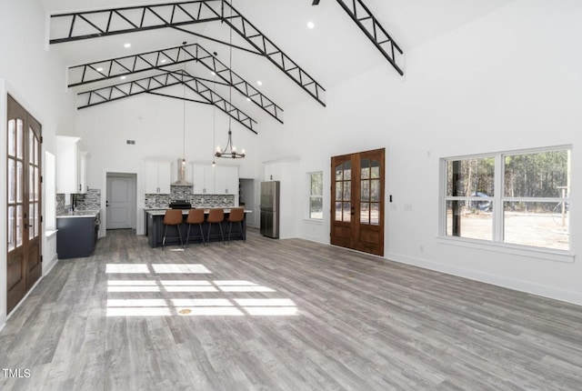 interior space with a high ceiling, french doors, and light wood-type flooring