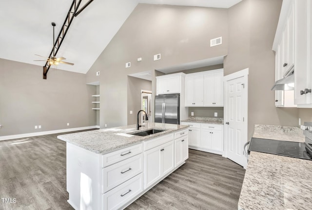 kitchen featuring stainless steel fridge, light hardwood / wood-style flooring, an island with sink, high vaulted ceiling, and ceiling fan