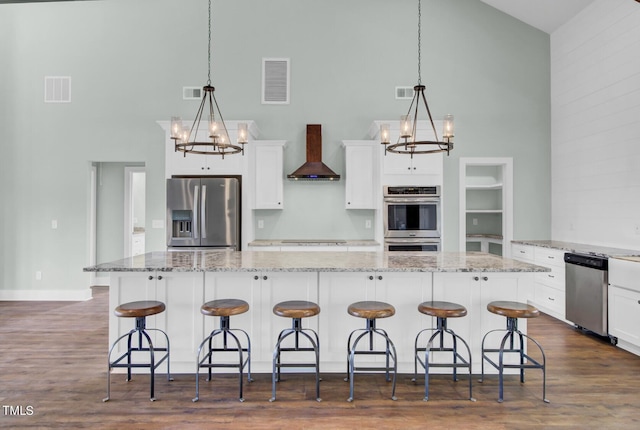 kitchen with decorative light fixtures, dark hardwood / wood-style flooring, stainless steel appliances, and wall chimney exhaust hood