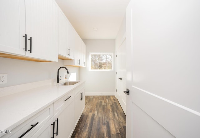 kitchen featuring white cabinetry, sink, dark hardwood / wood-style floors, and light stone counters