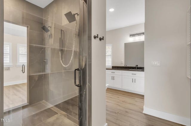 bathroom featuring a shower with shower door, hardwood / wood-style flooring, and vanity