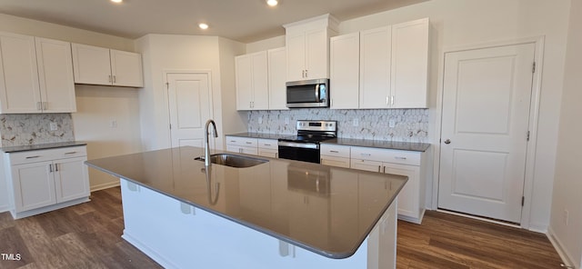 kitchen with an island with sink, tasteful backsplash, white cabinetry, appliances with stainless steel finishes, and sink