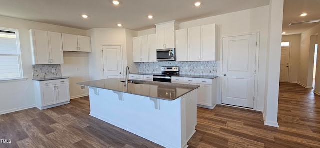 kitchen with appliances with stainless steel finishes, white cabinets, and a center island with sink