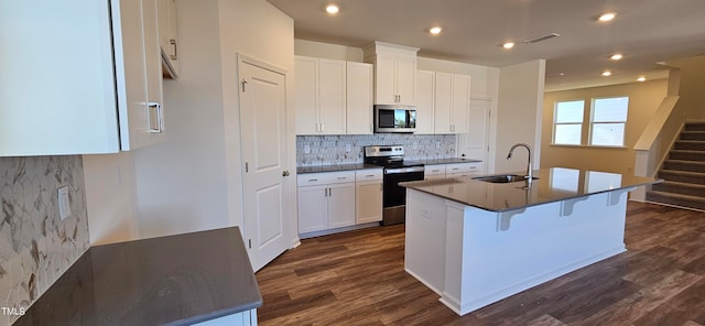 kitchen with stainless steel appliances, a center island with sink, white cabinets, and sink