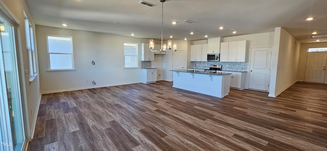 kitchen featuring white cabinets, dark hardwood / wood-style floors, an island with sink, and appliances with stainless steel finishes