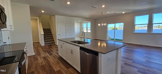 kitchen with sink, white cabinetry, an island with sink, stainless steel dishwasher, and a notable chandelier