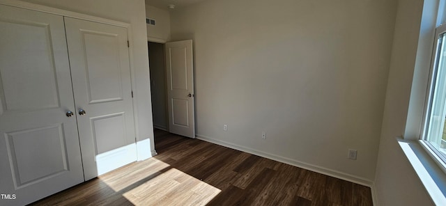 unfurnished bedroom with a closet and dark hardwood / wood-style floors