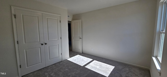 unfurnished bedroom featuring a closet and dark colored carpet