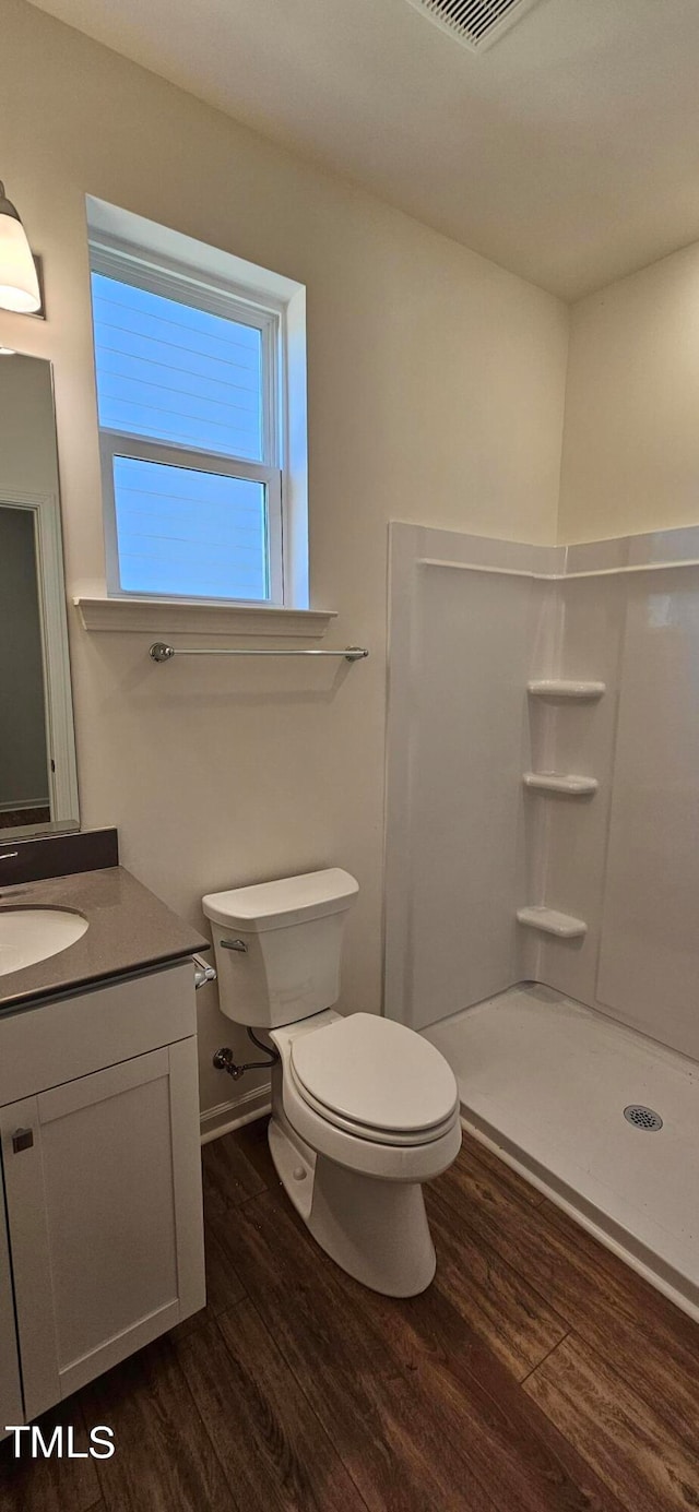 bathroom featuring toilet, a shower, wood-type flooring, and vanity