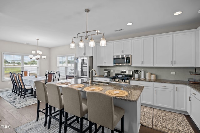 kitchen with stainless steel appliances, sink, an island with sink, and tasteful backsplash