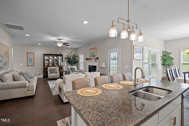 kitchen with dark hardwood / wood-style floors, ceiling fan, dark stone countertops, sink, and white cabinetry