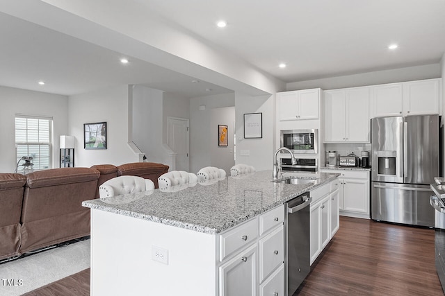 kitchen featuring dark hardwood / wood-style floors, a center island with sink, sink, white cabinetry, and appliances with stainless steel finishes