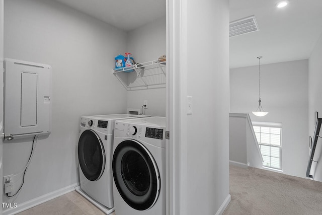 washroom featuring electric panel, washer and dryer, and light colored carpet