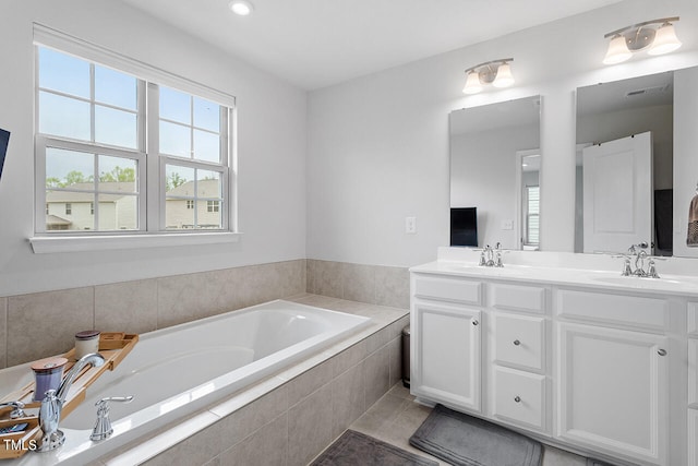 bathroom with vanity, a relaxing tiled tub, and tile patterned flooring