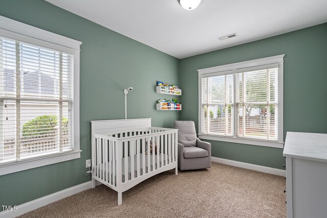 carpeted bedroom featuring a nursery area