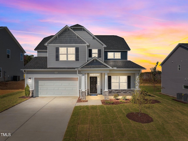 craftsman-style home featuring a yard, a garage, and central AC unit