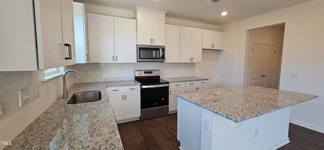 kitchen featuring white cabinetry, appliances with stainless steel finishes, a center island, and light stone countertops