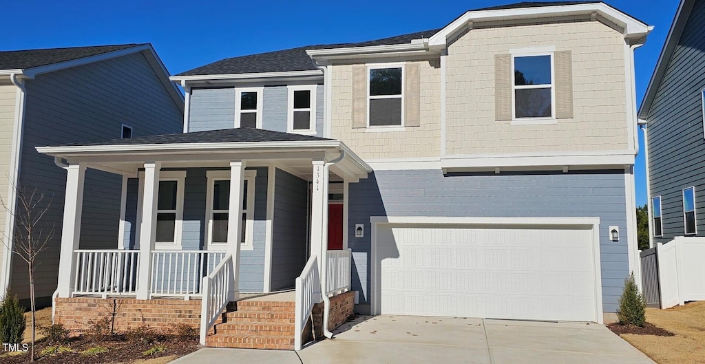 traditional home with an attached garage, covered porch, and driveway