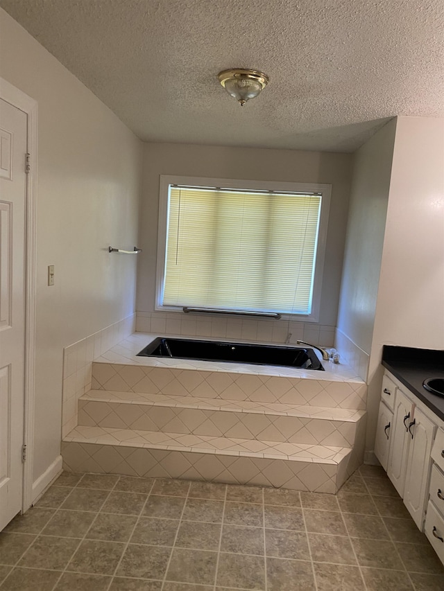 bathroom featuring tile floors, tiled bath, a textured ceiling, and vanity