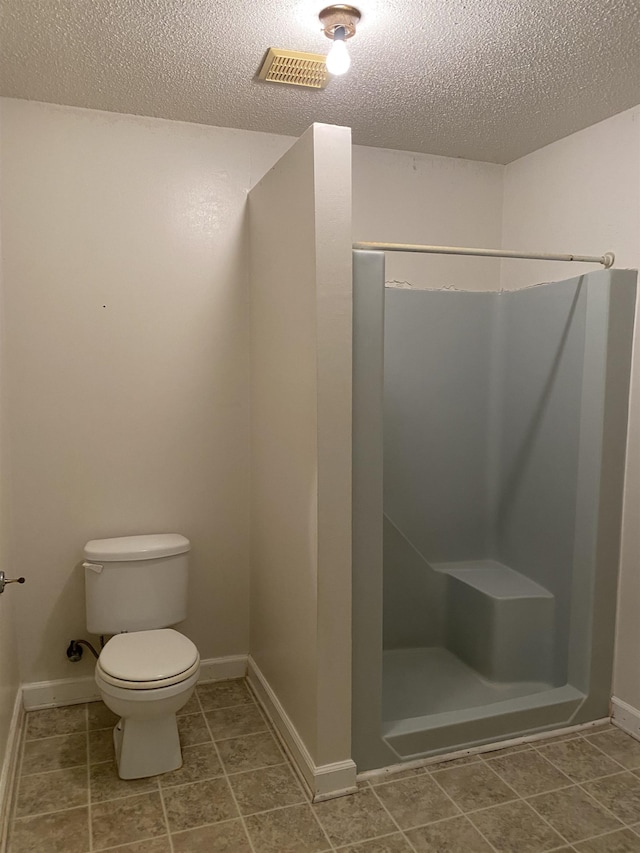 bathroom featuring tile flooring, toilet, and a textured ceiling