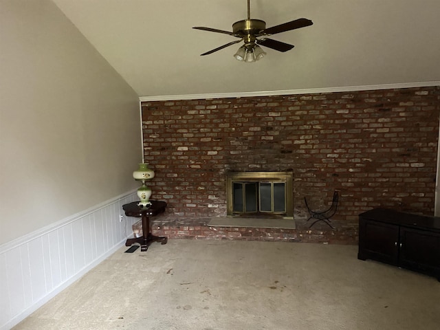 unfurnished living room with ceiling fan, vaulted ceiling, carpet flooring, a brick fireplace, and brick wall