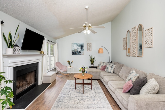 living room featuring ceiling fan, vaulted ceiling, a textured ceiling, and dark wood-type flooring