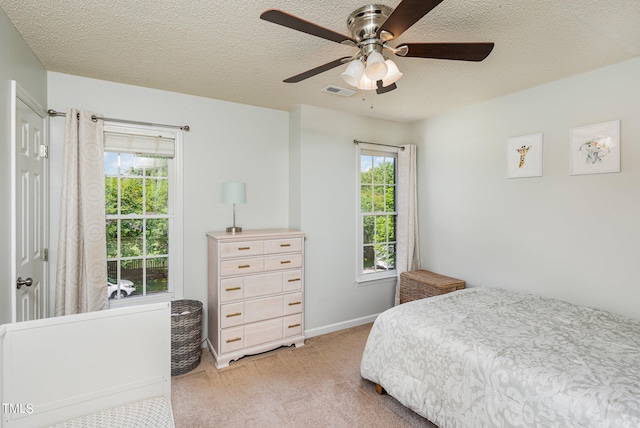 bedroom featuring light carpet, ceiling fan, and a textured ceiling