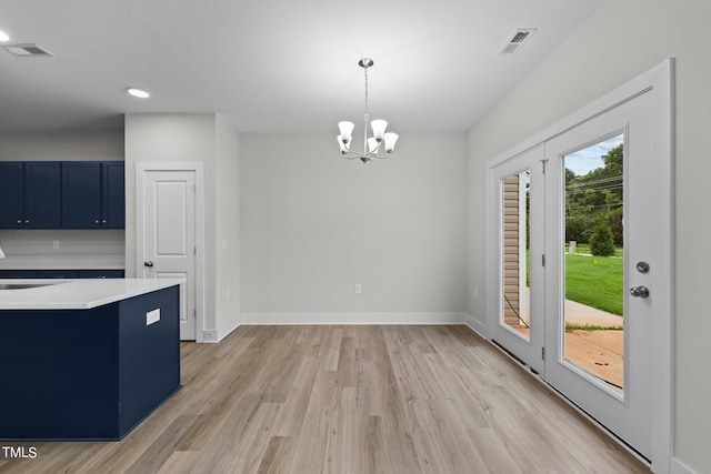 kitchen with blue cabinets, sink, decorative light fixtures, a chandelier, and light wood-type flooring