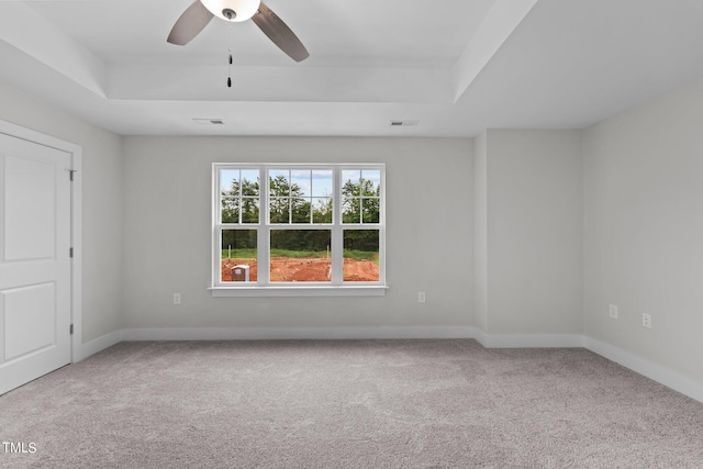 carpeted empty room featuring a raised ceiling and ceiling fan