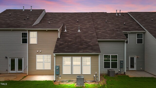 back house at dusk with cooling unit, a yard, and a patio