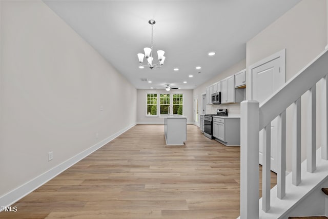 kitchen featuring gray cabinets, appliances with stainless steel finishes, decorative light fixtures, light hardwood / wood-style floors, and an inviting chandelier