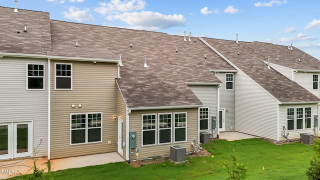 back of property featuring a lawn and central air condition unit