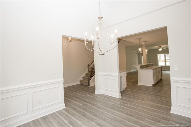 816 Red Hawk Pl, Vass, NC 28394 - unfurnished dining area with a chandelier, stairs, a decorative wall, wainscoting, and light wood-style flooring
