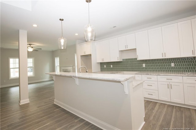816 Red Hawk Pl, Vass, NC 28394 - kitchen featuring backsplash, a kitchen island with sink, recessed lighting, wood finished floors, and white cabinetry