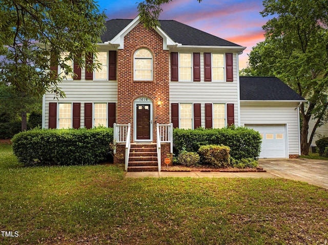 colonial house featuring a garage and a lawn