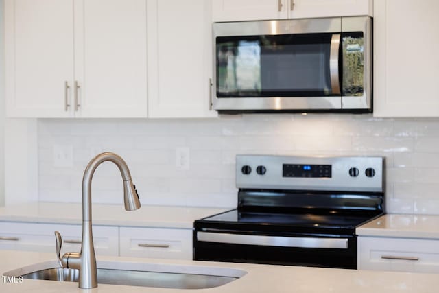 kitchen with white cabinets, appliances with stainless steel finishes, decorative backsplash, and sink