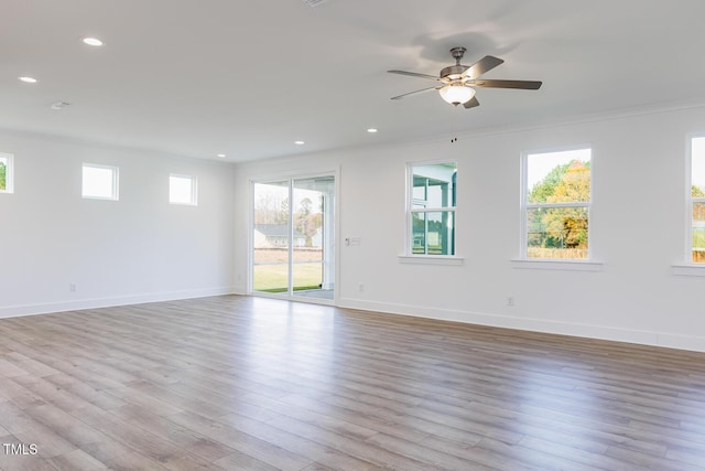 empty room with crown molding, a healthy amount of sunlight, and light wood-type flooring